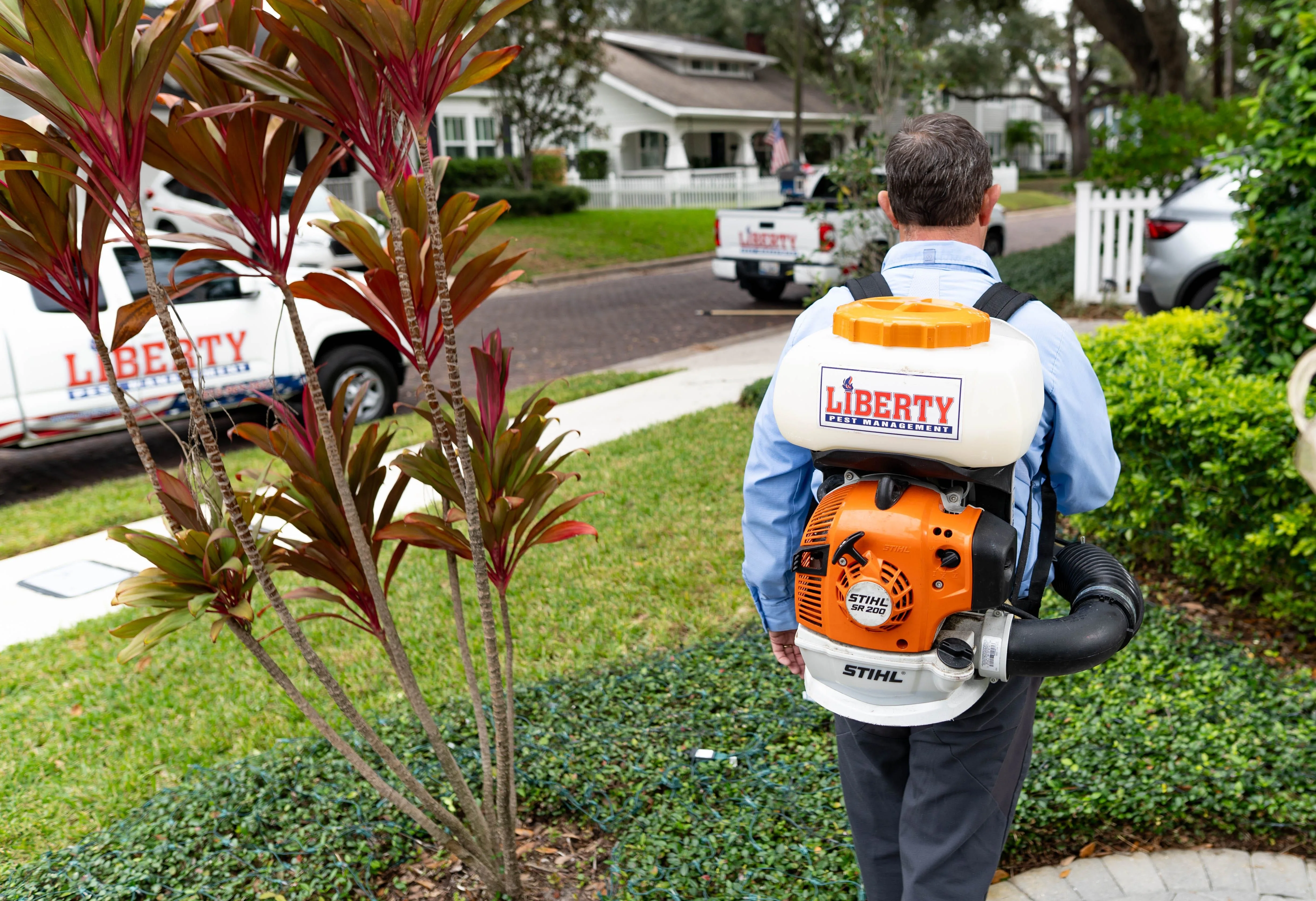 A Liberty Pest Management technician applying mosquito barrier treatment in a Tampa Bay neighborhood